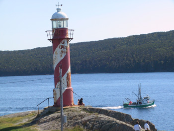 fishing boat passes by lighthouse at Hearts Content 